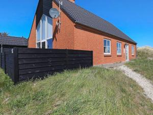 a red brick house with a black fence in front of it at 8 person holiday home in Hanstholm in Vigsø