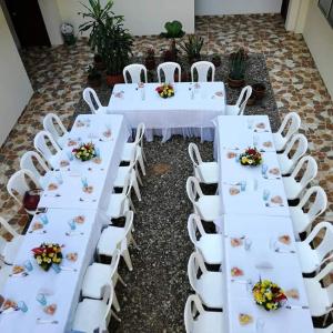 a row of white tables and chairs with flowers on them at Hotel Prado Country in Aguachica