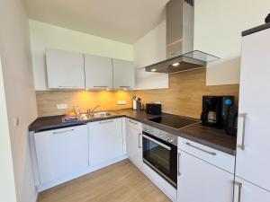 a kitchen with white cabinets and a sink at Apartments Gezeitenfluss in Tönning