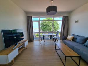 a living room with a couch and a tv and a table at Apartments Gezeitenfluss in Tönning