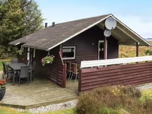Bøstrupにある6 person holiday home in H jslevの木製デッキ(テーブル、椅子付)が備わるキャビンです。