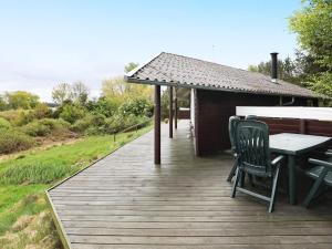una terraza de madera con mesa y sillas. en 6 person holiday home in H jslev, en Bøstrup