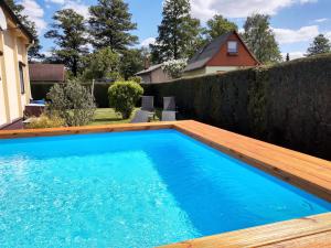 una piscina en un patio trasero con una terraza de madera y una piscina azul en Ferienhaus am Kamskefliess en Lübbenau