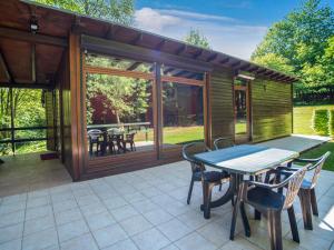 a screened in porch with a table and chairs at Cozy Chalet in Trois Ponts with Forest Near in Trois-Ponts