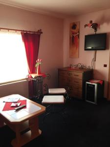 a living room with a table and a dresser with a television at Penzion starojicka pizza in Starý Jičín