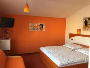 1 dormitorio con paredes de color naranja, 1 cama y TV en Penzion starojicka pizza, en Starý Jičín