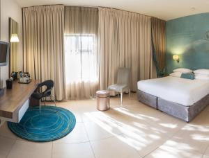 a hotel room with a bed and a desk and a desk at Metcourt at Emperors Palace in Kempton Park