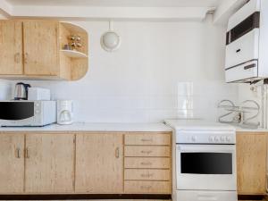 eine Küche mit weißen Geräten und Holzschränken in der Unterkunft Lovely Cottage in Pontgibaud with Garden near Lake in Pontgibaud