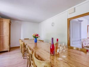 einen langen Holztisch mit Weinflaschen und Stühlen in der Unterkunft Lovely Cottage in Pontgibaud with Garden near Lake in Pontgibaud