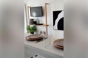 a table with plates and a tv on a wall at NOUVELLE VAGUE Modern Ocean View STUDIO w balcony - Swimming Pool in Biarritz