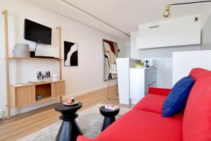 a living room with a red couch and a kitchen at NOUVELLE VAGUE Modern Ocean View STUDIO w balcony - Swimming Pool in Biarritz +15 photos