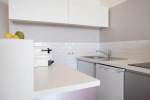 a white kitchen with a sink and a dishwasher at NOUVELLE VAGUE Modern Ocean View STUDIO w balcony - Swimming Pool in Biarritz