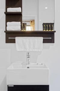 baño con lavabo blanco y estante con toallas en KOZYGURU Belrose Modern Designer 2 Bed FREE Parking NBE007, en Belrose