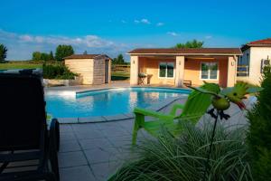 a swimming pool with a green chair and a house at Gîte le pastel in Puéchoursi