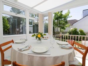 een eetkamer met een tafel, stoelen en ramen bij Garden View in Newquay
