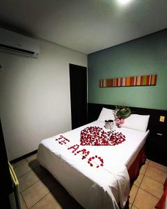 um quarto com uma cama com rosas vermelhas em Pousada do sol Meaipe em Guarapari