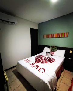 a bedroom with a bed with red roses on it at Pousada do sol Meaipe in Guarapari