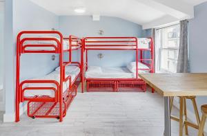a room with red bunk beds and a table at Astor Kensington Hostel in London