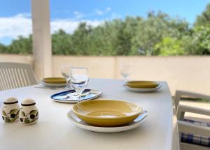 een tafel met borden, kommen en glazen erop bij Apartments Pijaza in Rab