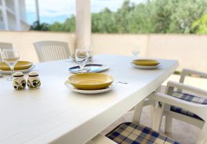 una mesa blanca con platos y copas de vino. en Apartments Pijaza, en Rab