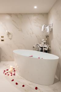a white bath tub in a bathroom with roses on the floor at Villa Nicolli Romantic Spa Resort - Adults Only in Riva del Garda