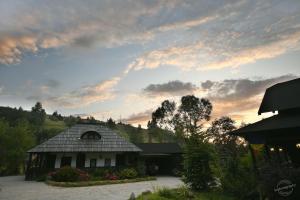 a house with a roof with a sunset in the background at Casa Poveste Pensiunea-Muzeu in Câmpulung Moldovenesc