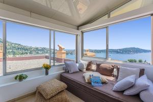 a living room with a couch and large windows at MY CASA - VILLEFRANCHE CAUVIN - Panoramic Sea View AC in Villefranche-sur-Mer