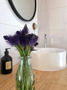 a vase with purple flowers sitting on a bathroom counter at Gites à la ferme à 5 minutes du lac de Gerardmer. in Sapois