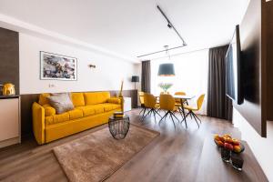 uma sala de estar com um sofá amarelo e uma mesa em Gerharts Premium City Living - center of Brixen with free parking and Brixencard em Bressanone