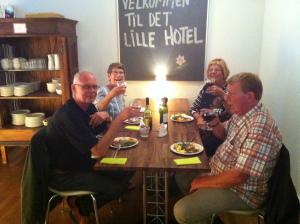 eine Gruppe von Menschen, die an einem Tisch sitzen und Wein trinken in der Unterkunft Det Lille Hotel in Rønne