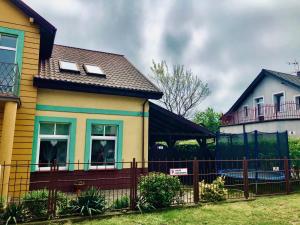 a yellow house with a fence in front of it at Dom gościnny u Gerliz in Rewal