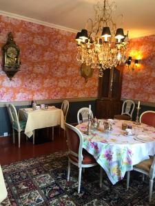 une salle à manger avec deux tables et un lustre dans l'établissement Manoir des Lions de Tourgéville, à Deauville