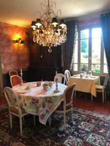 a dining room with a table and chairs and a chandelier at Manoir des Lions de Tourgéville in Deauville