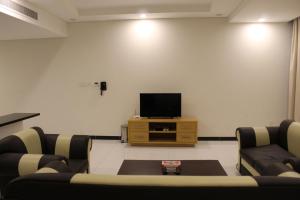 sala de estar con TV de pantalla plana y sillas en Asian Tower, en Al Ghurayfah