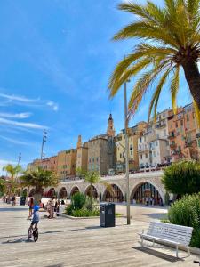a child riding a bike in a city with a palm tree at Les Sablettes in Menton