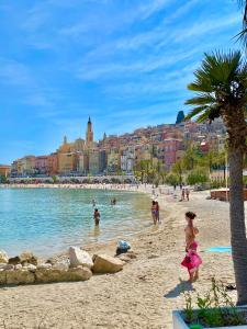 a group of people on a beach near the water at Les Sablettes in Menton