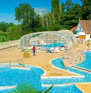 a pool with two swimming pools and a glass house at Bungalow de 3 chambres avec piscine partagee et terrasse amenagee a Trogues in Trogues