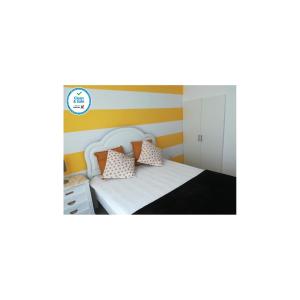 um quarto com uma cama branca com riscas laranja e amarela em Casa da Avó Lucinda na Nazaré