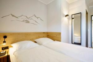 a bedroom with two white beds and a mirror at Gasthof Neuwirt Unterföhring in Munich