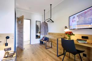 a living room with a desk and a tv on the wall at Gasthof Neuwirt Unterföhring in Munich