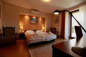 a bedroom with a bed and a desk and a chair at Fürjes Villa Panzió in Balatonfüred