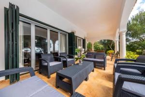 un patio con sillas, mesas y ventanas en Villa Luxury, en Binibeca