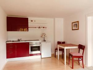 a kitchen with red cabinets and a table with chairs at Ferienwohnung Watzmann - Haus Martin in Bischofswiesen