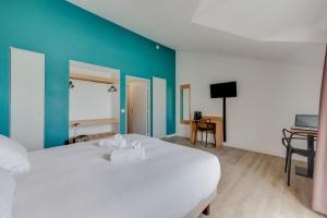 カンヌにあるレジドホテル レ コラリヌのベッドルーム1室(白いベッド1台、青い壁付)
