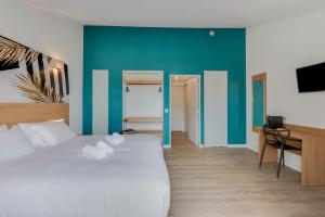 a bedroom with a white bed and a blue wall at Residhotel Les Coralynes in Cannes