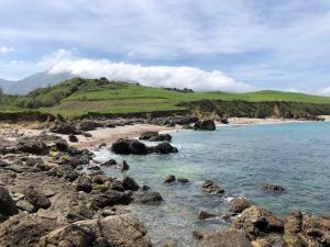 a beach with rocks and the ocean and a hill at HOTEL CARAVIA in Caravia