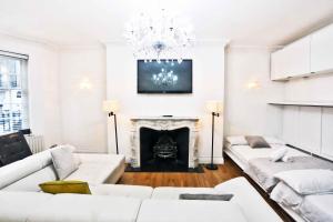 a living room with white furniture and a fireplace at L'ambassadeur 9room Belgravia Embassies TownHouse in London