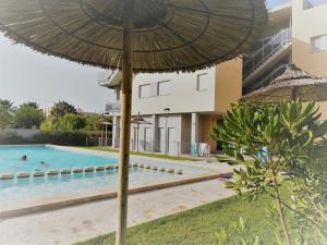a pool with an umbrella next to a building at Apartamento Paraiso Beach in Daimuz