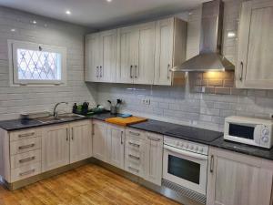 a kitchen with white cabinets and a sink and a microwave at Villa Elena in Salou