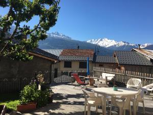 a patio with tables and chairs with mountains in the background at Chez polyte in Bourg-Saint-Maurice